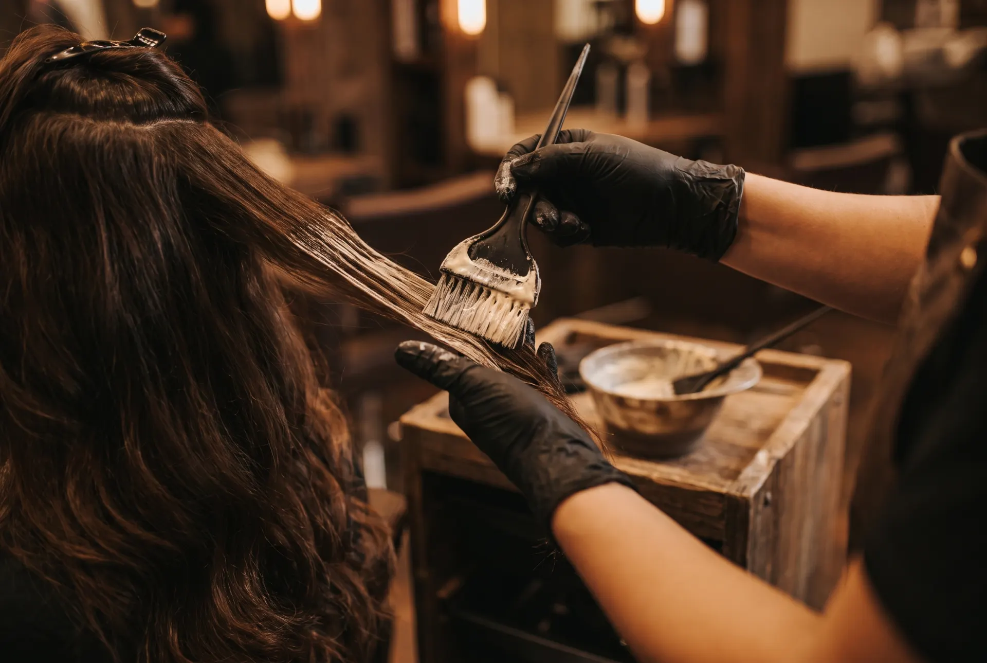 Frisör penslar balayage för hand på långt brunt hår